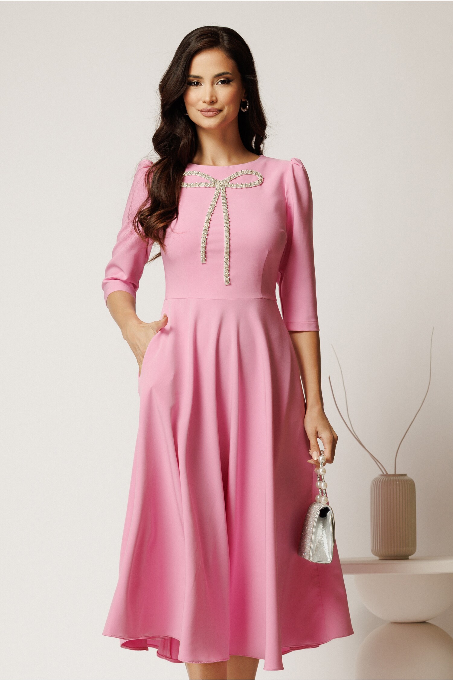 Rochie midi roz din stofa in clos cu funda si strasuri pe bust